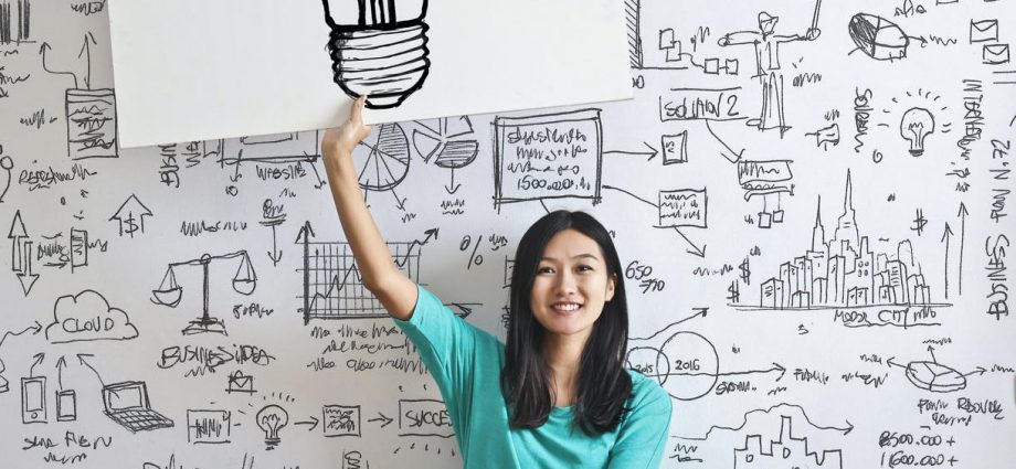 woman draw a light bulb in white board