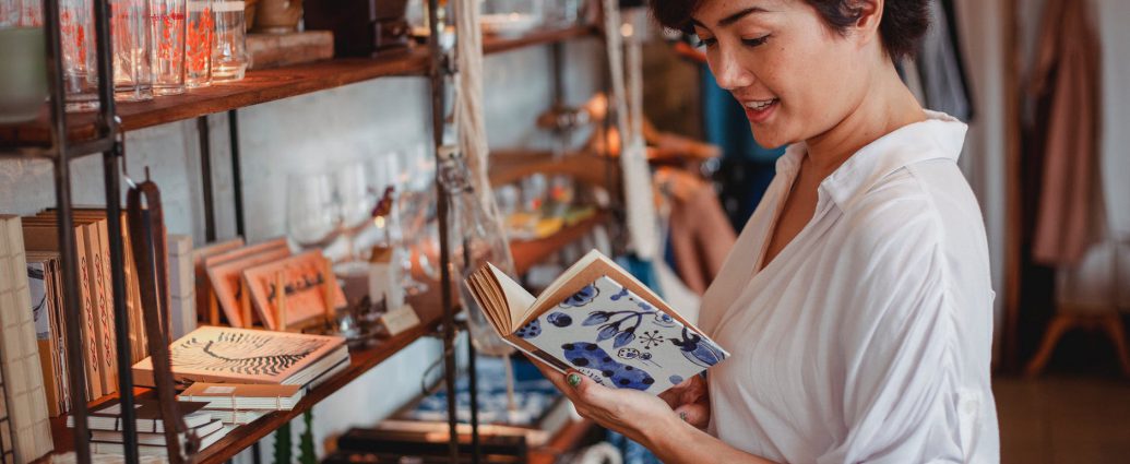 gorgeous asian young lady reading novel in vintage boutique