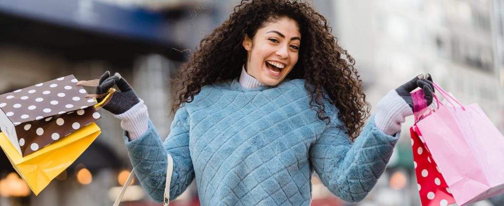 happy ethnic woman demonstrating shopping bags