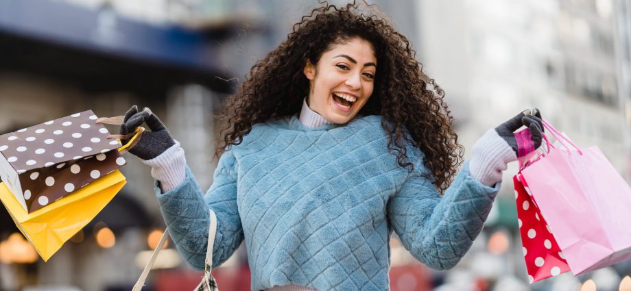 happy ethnic woman demonstrating shopping bags
