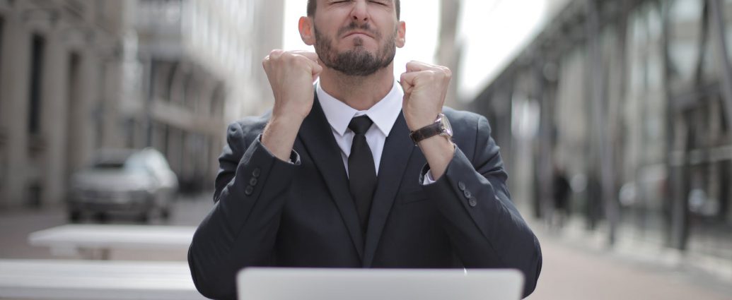 man in black suit sitting on chair beside buildings