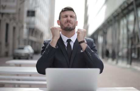 man in black suit sitting on chair beside buildings