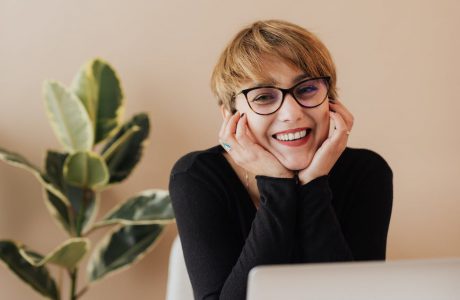 cheerful woman smiling while sitting at table with laptop
