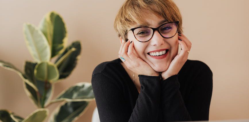 cheerful woman smiling while sitting at table with laptop